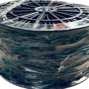 A large, black spool wrapped in clear plastic holds a long coil of green wire